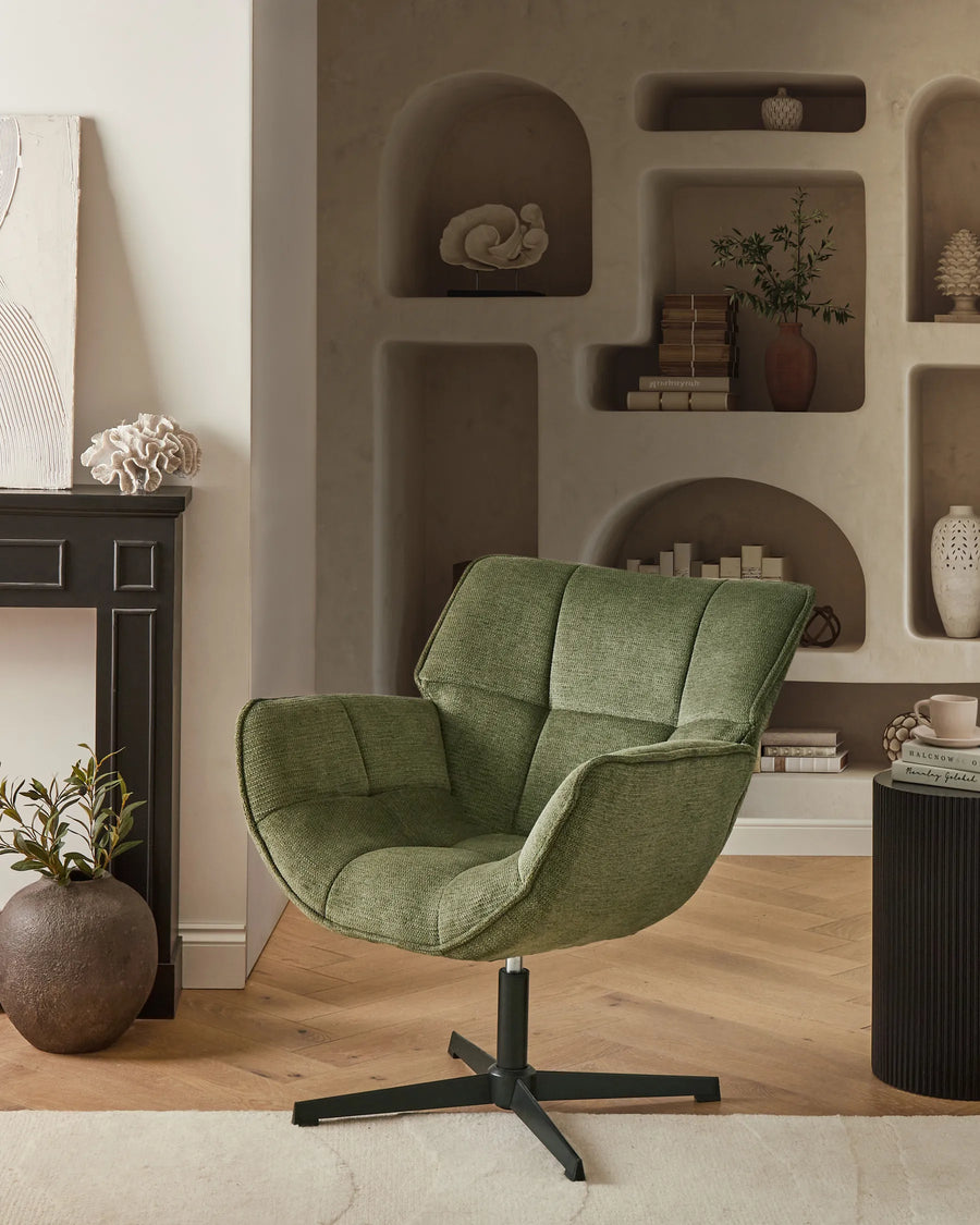 Green armchair in a living room with shelves and decor