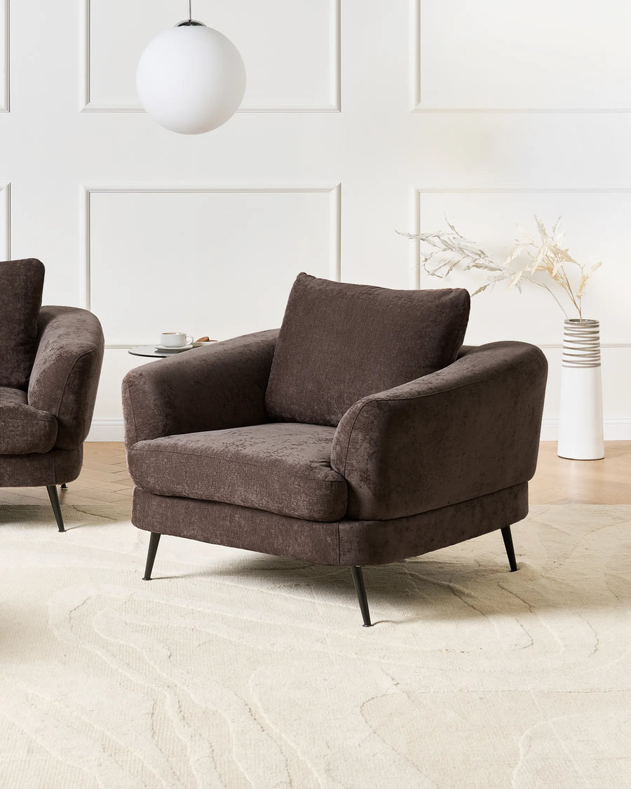 Brown armchair in a modern living room setting with a white wall and light wood floor.