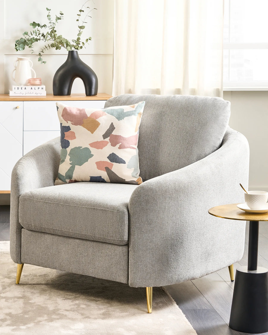 Gray armchair with a colorful pillow in a living room setting