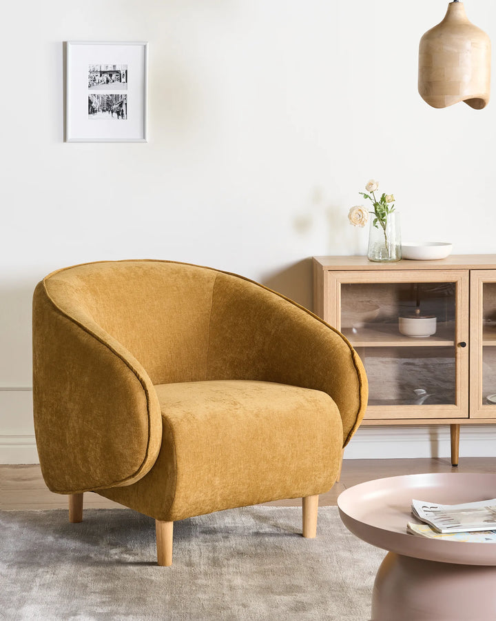 Mustard yellow armchair in a living room setting with a coffee table and cabinet.