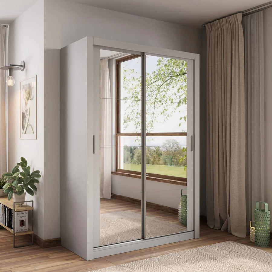 Sliding wardrobe with mirror doors in a room with curtains and a plant.