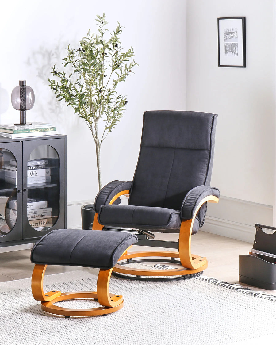 Black recliner chair with wooden armrests and matching ottoman in a room with a plant and cabinet.