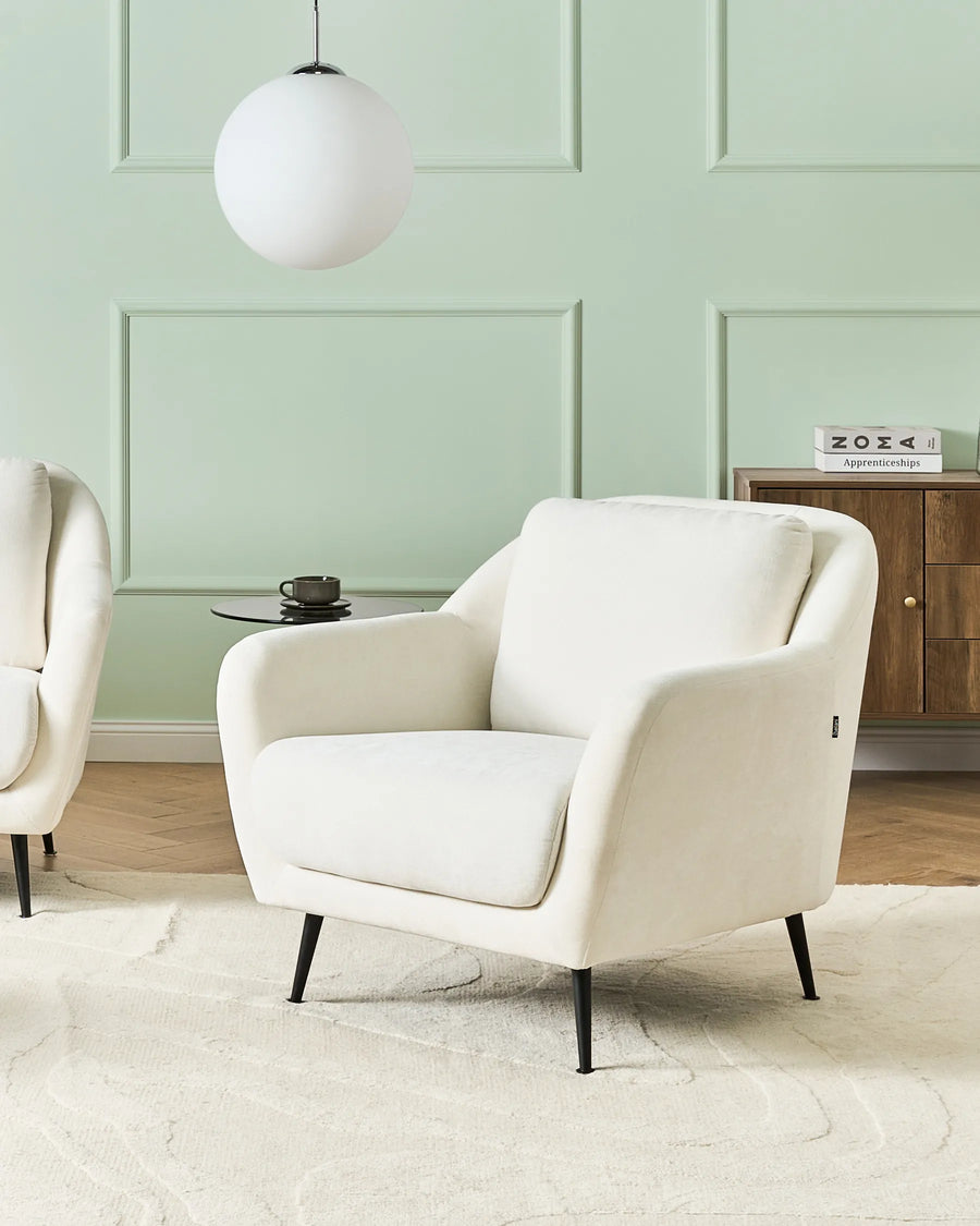 White armchair in a room with a light green wall and wooden cabinet.
