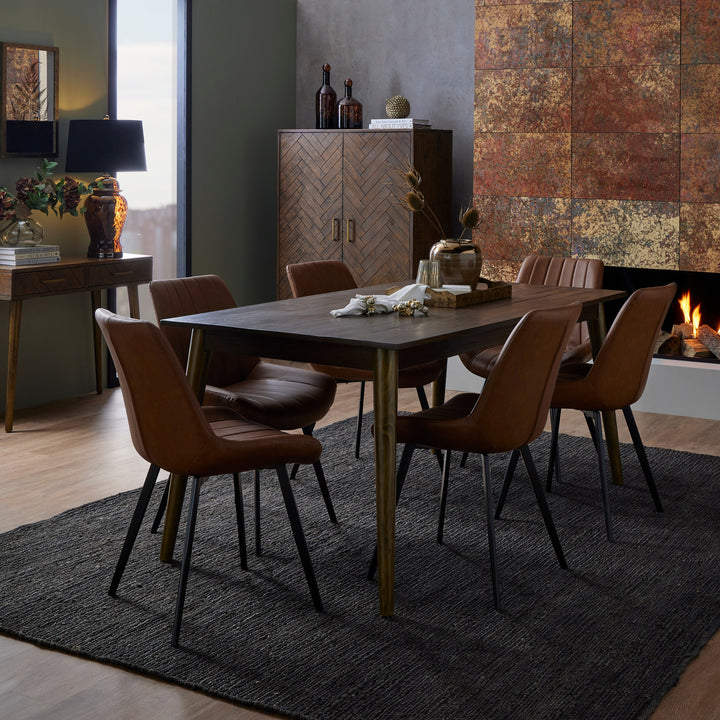 Dining room with wooden table and chairs in front of a fireplace.