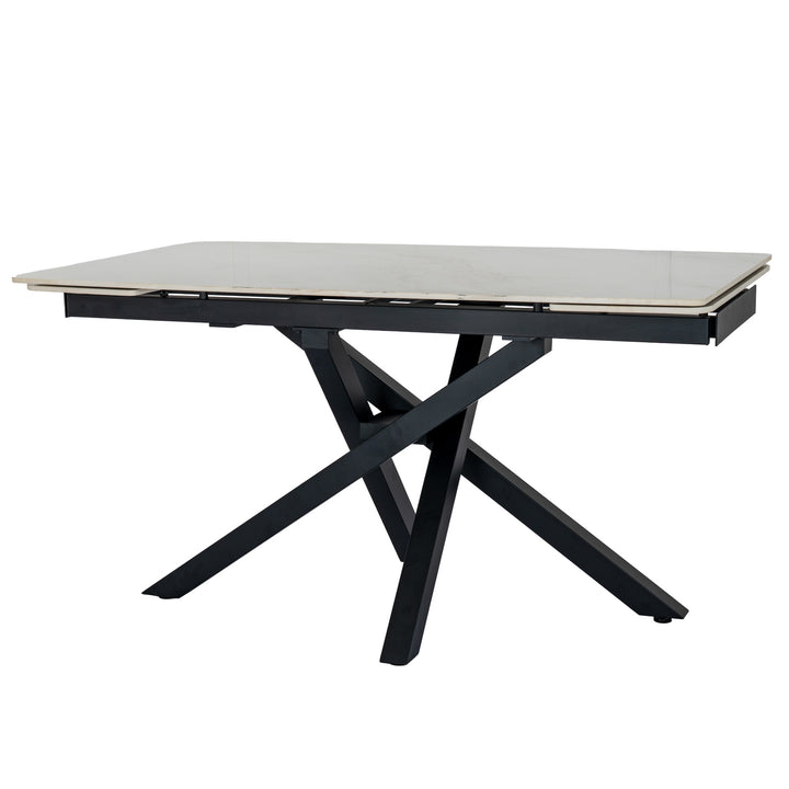 A modern rectangular dining table with a light beige stone or laminate top and a black metal frame featuring an X-shaped base, shown on a plain white background.