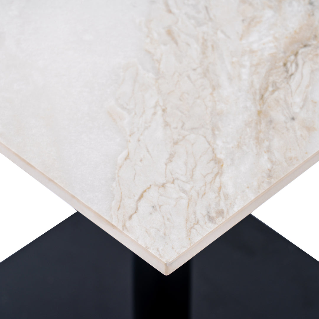 Close-up of a rectangular table corner with a white marble-look top featuring soft beige and cream veining, set against a black pedestal base on a white background.