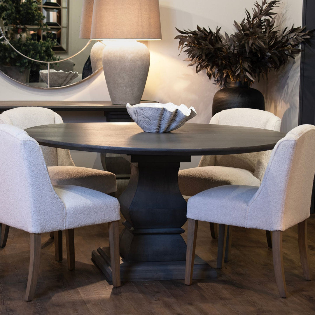 Dining room with a round dark wooden table and white chairs.