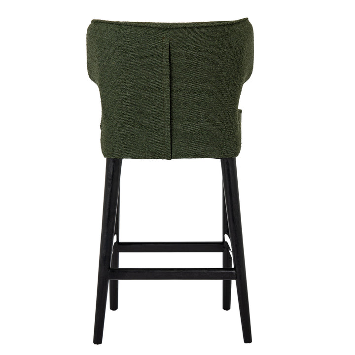 An upholstered bar stool with a textured dark green fabric seat and backrest, supported by four black wooden legs and a footrest.