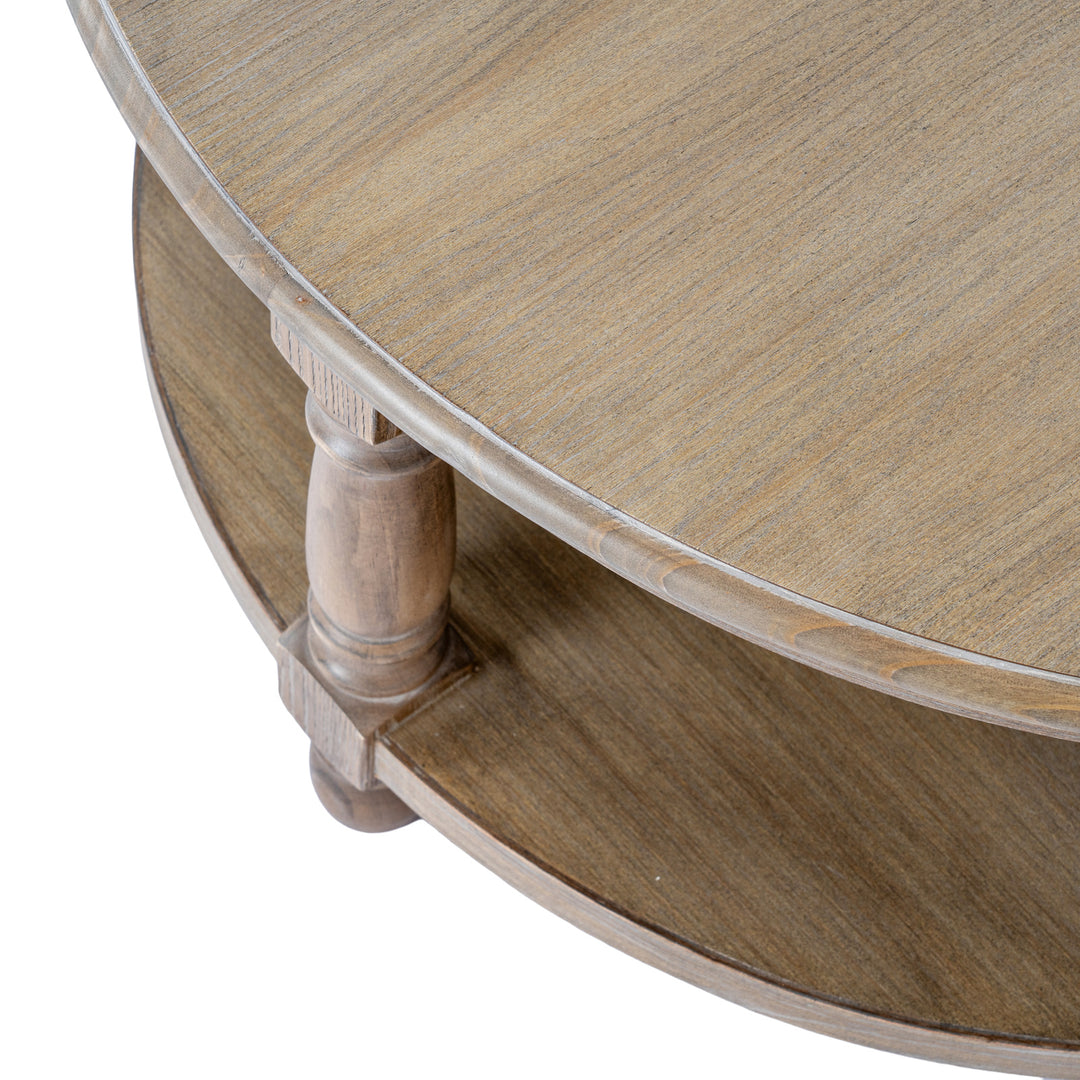 Close-up detail of a round wooden coffee table with a glass top, showing the wood grain, turned leg, and lower shelf on a white background.
