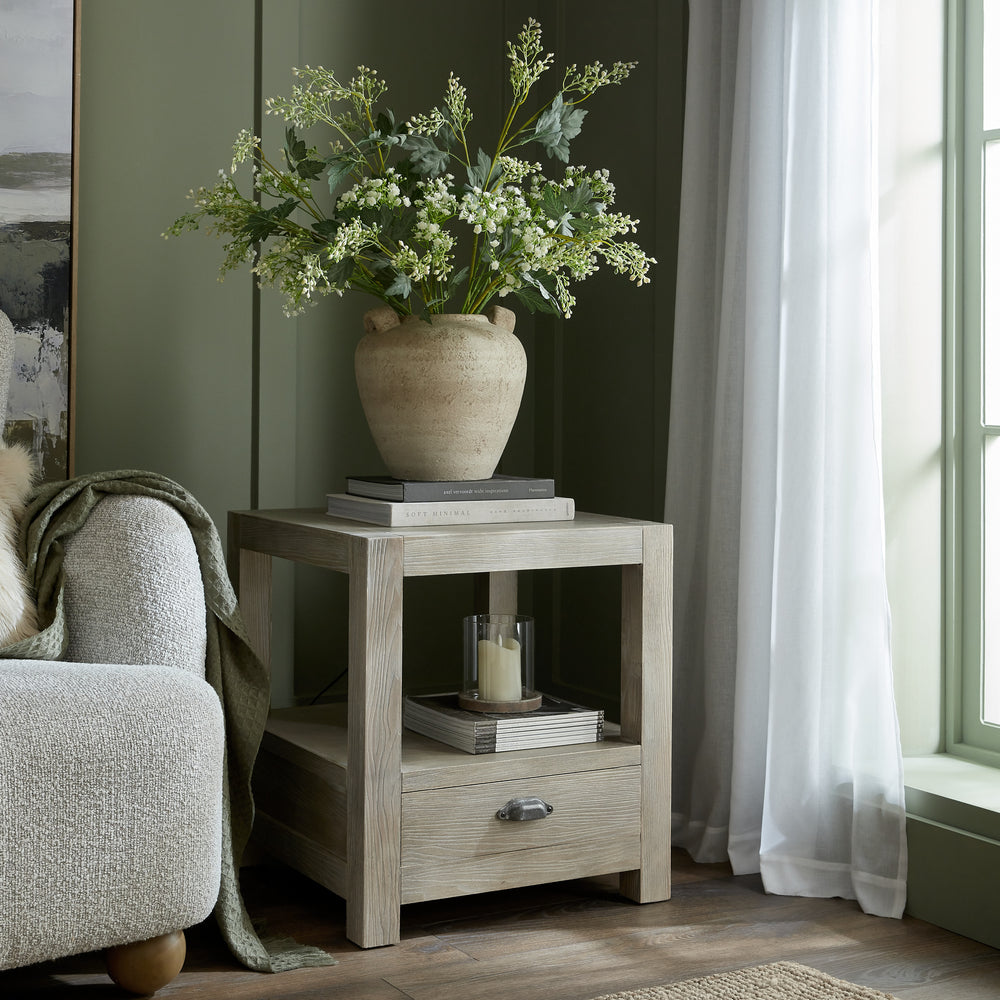 Wooden side table with a vase of flowers in a living room setting