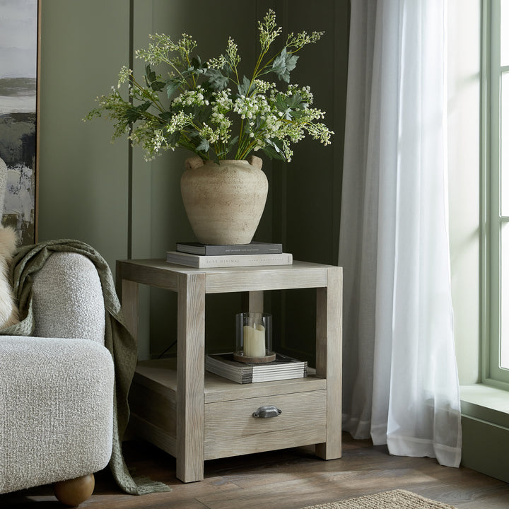 Wooden side table with a vase of flowers in a living room setting