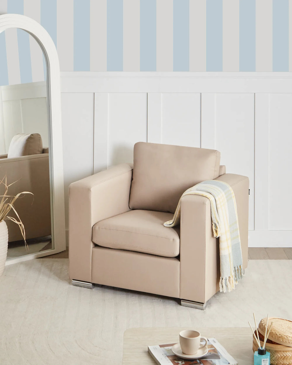 Beige armchair with a blanket against a wall with blue and white stripes