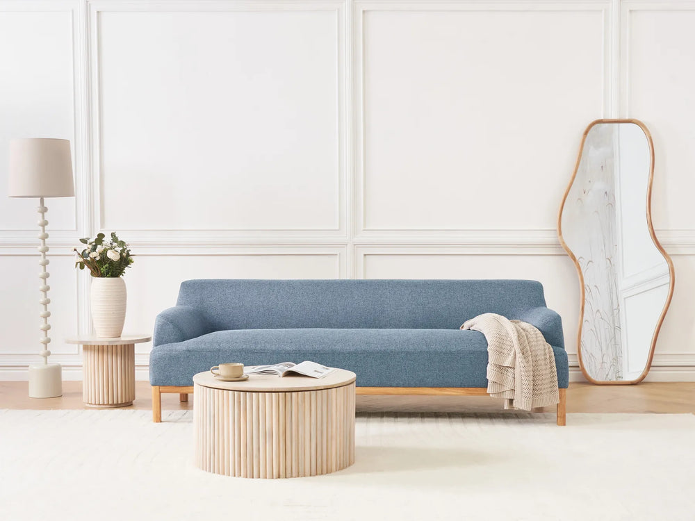 Modern living room with a blue sofa, wooden coffee table, and decorative items.
