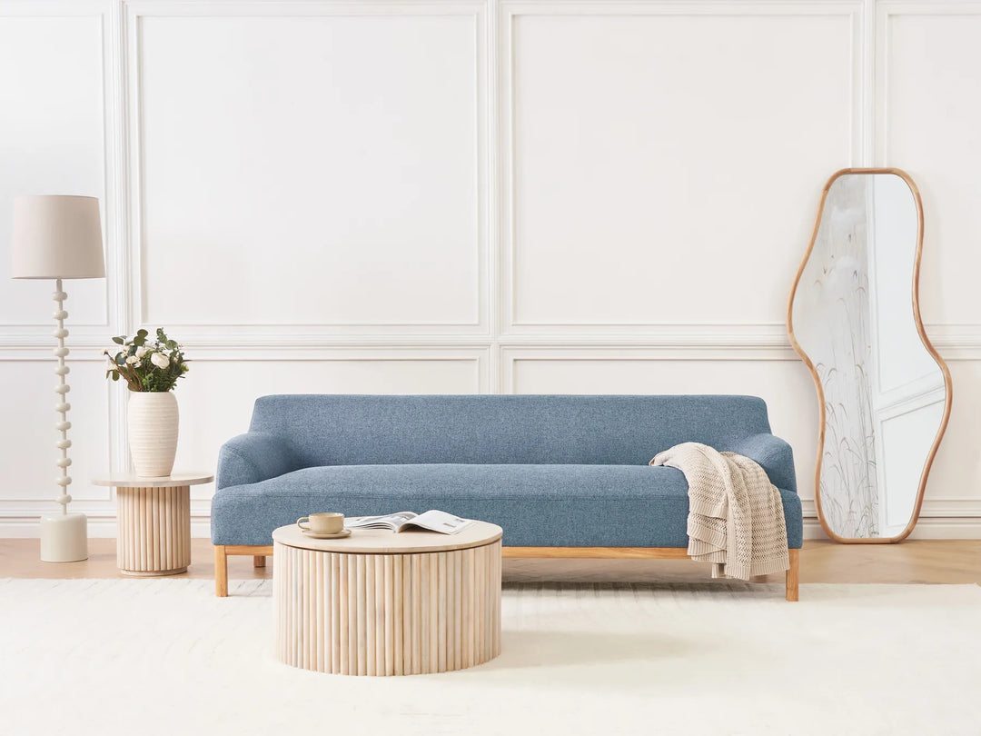 Modern living room with a blue sofa, wooden coffee table, and decorative items.