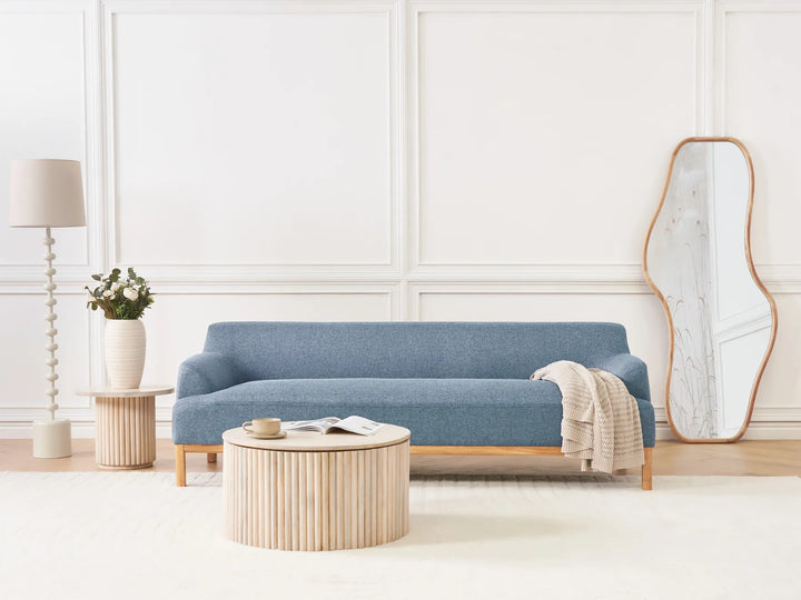 Modern living room with a blue sofa, wooden coffee table, and decorative items.