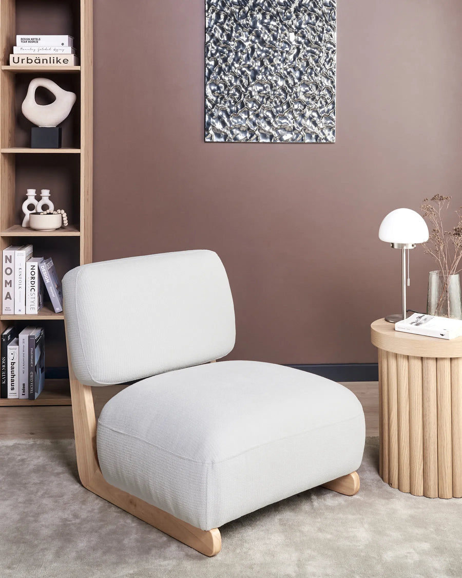 Modern gray armchair in a room with a bookshelf and side table.
