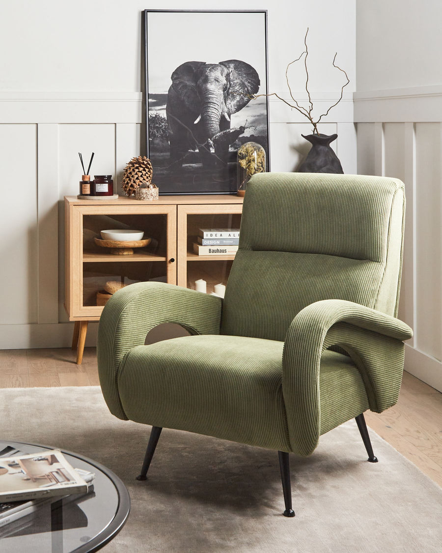 Green armchair in a room with a wooden cabinet and decorative items.