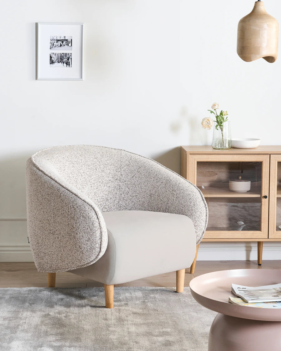 Modern living room with a gray armchair, coffee table, and wooden cabinet.