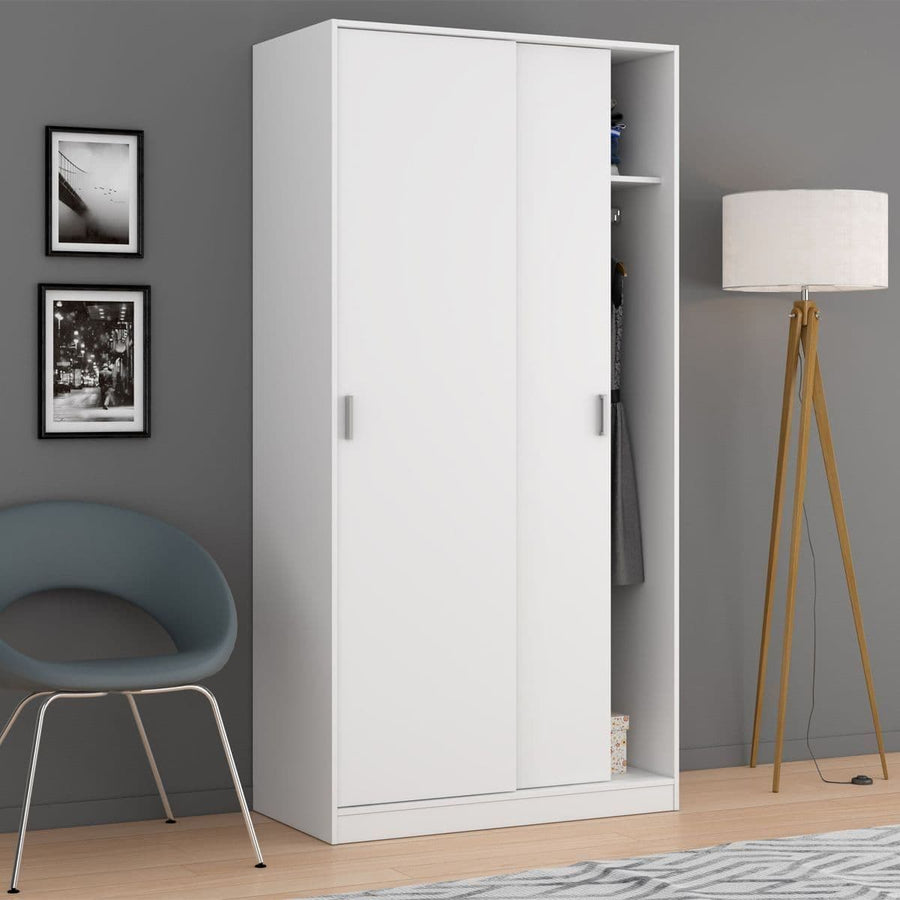 White wardrobe with sliding doors in a room with a chair, lamp, and framed pictures on the wall.