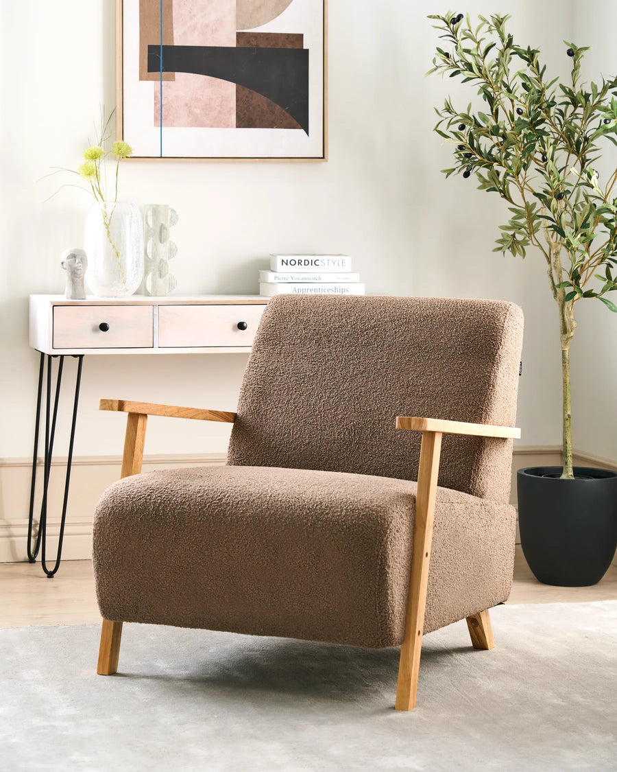 Brown armchair in a room with a side table, books, and a plant.