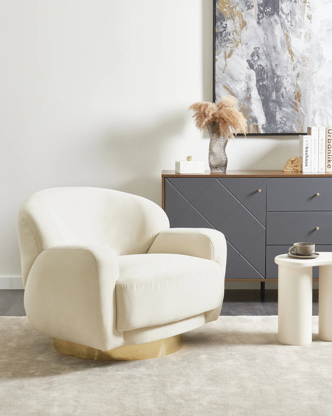 Beige armchair in a living room with a gray sideboard and abstract art on the wall.