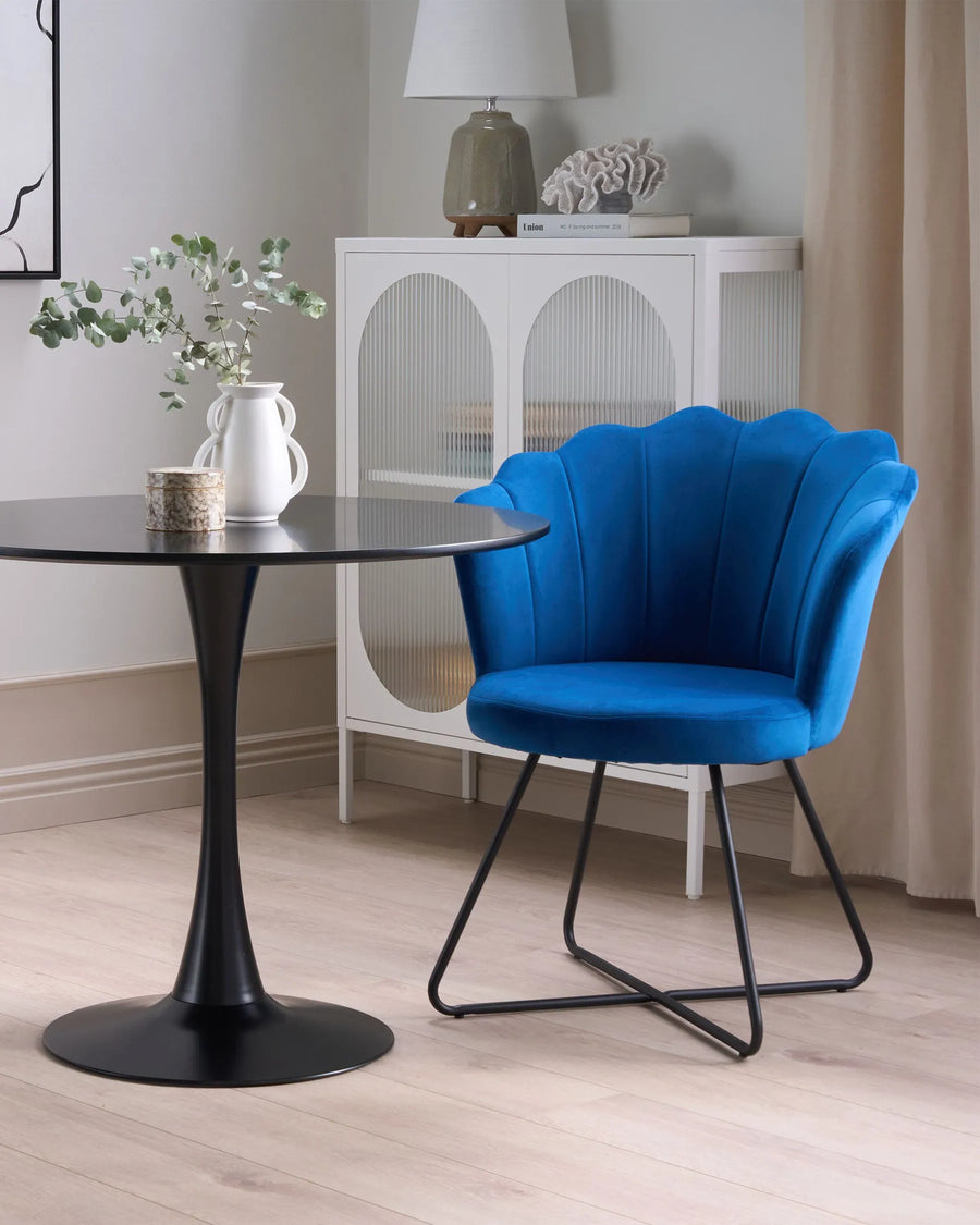 Blue chair with black metal legs next to a round black table in a room.