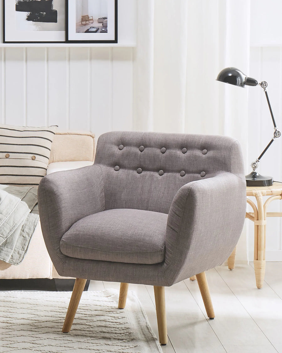 Gray armchair in a living room setting with a lamp and pillows.