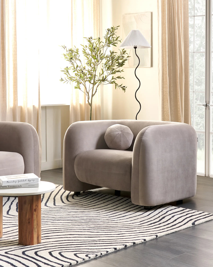Modern living room with a gray armchair, coffee table, and decorative plant.