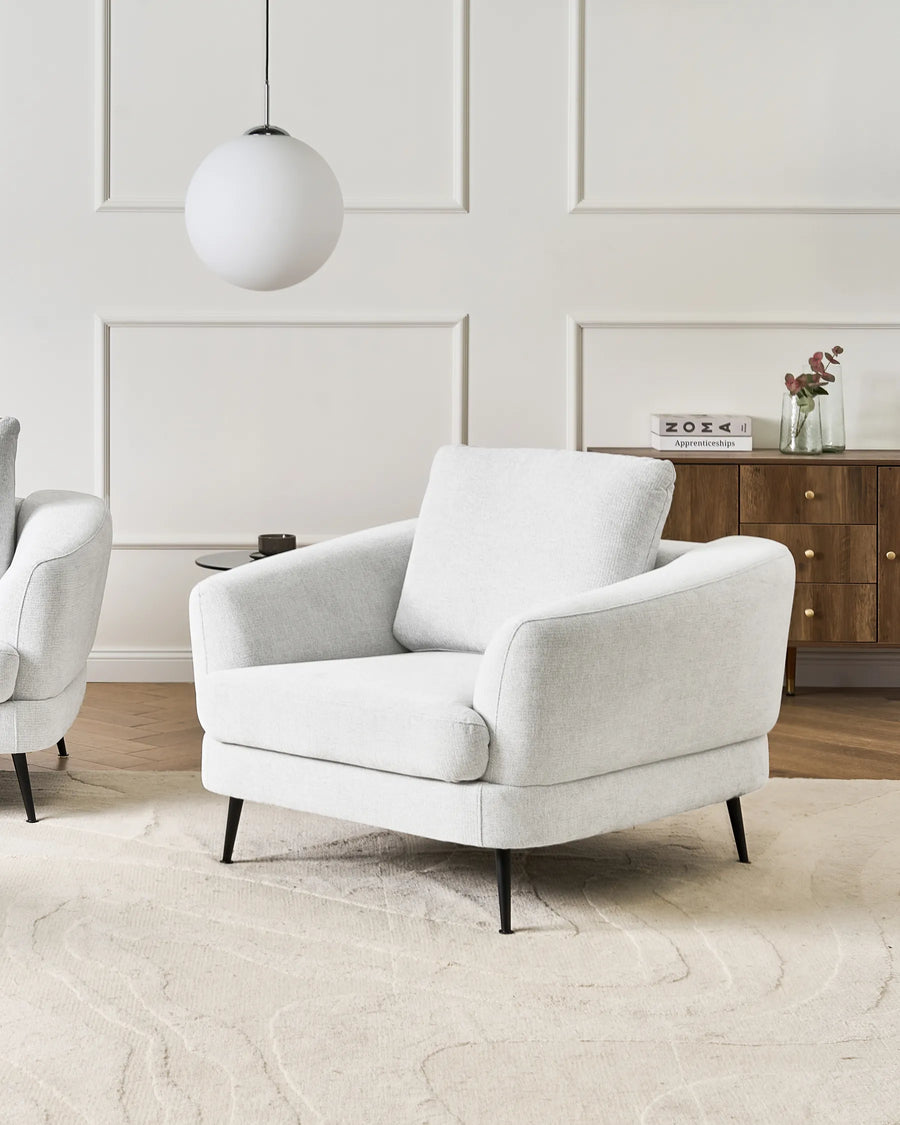 White armchair in a modern living room with a neutral color palette.