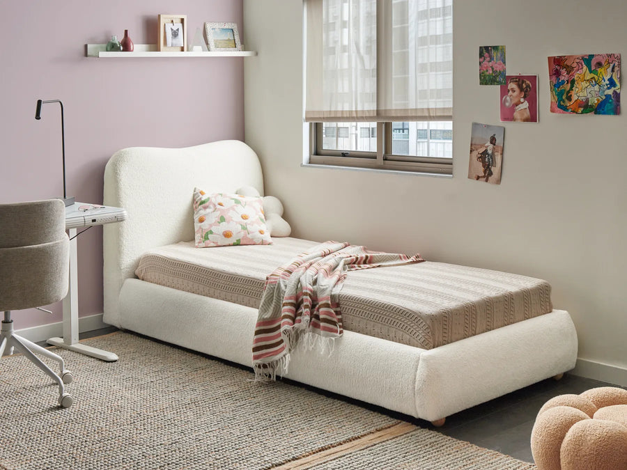 White upholstered bed in a room with a window, shelves, and decorative items.