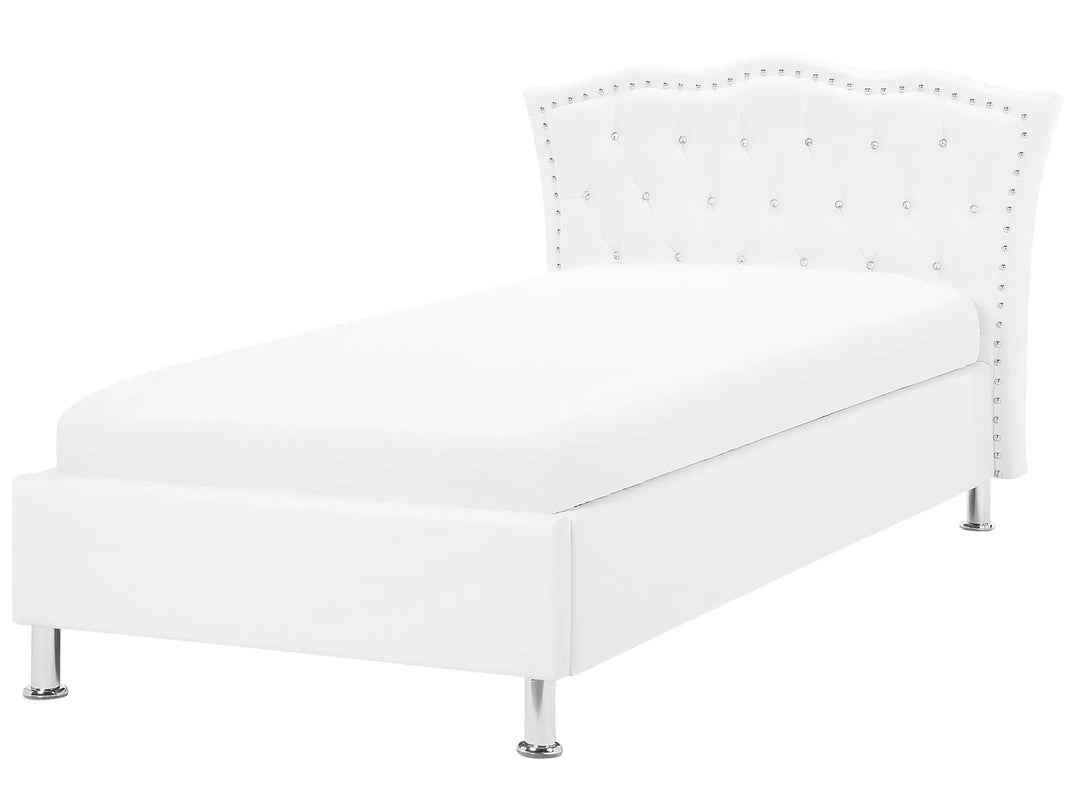 White upholstered bed with decorative nailhead trim on a white background