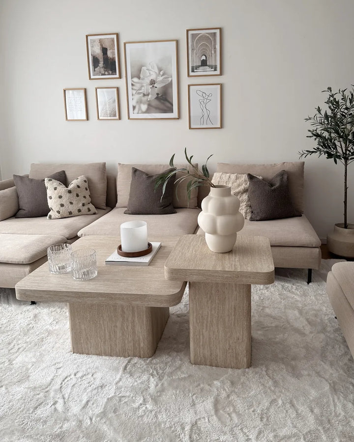 Modern living room with a beige sectional sofa, wooden coffee table, and decorative wall art.