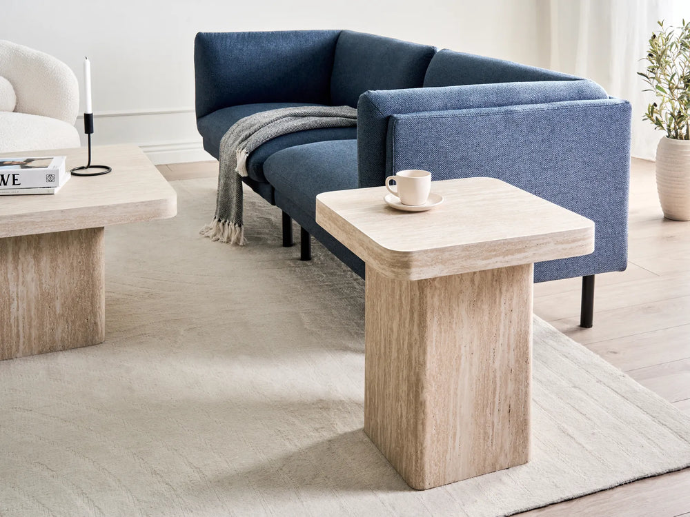 Modern living room with a blue sofa, wooden coffee table, and decorative items.