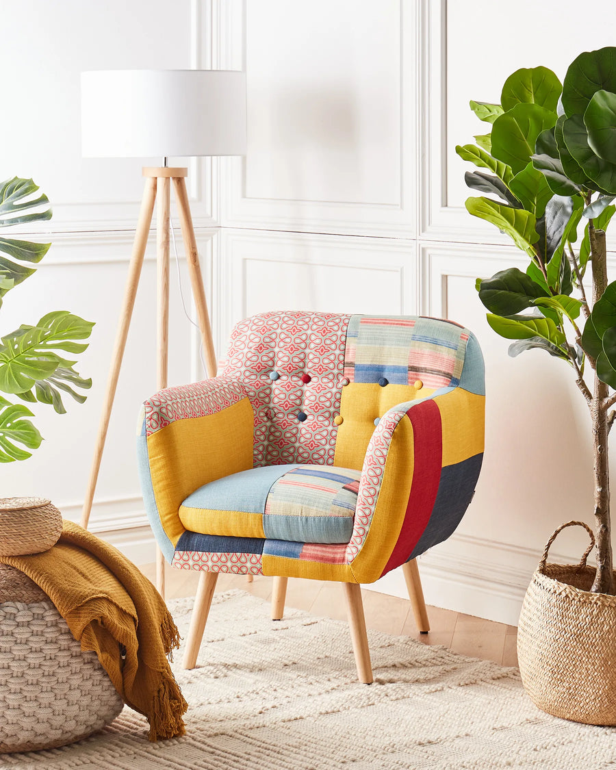 Multicolored patchwork chair in a bright room with plants and a lamp.