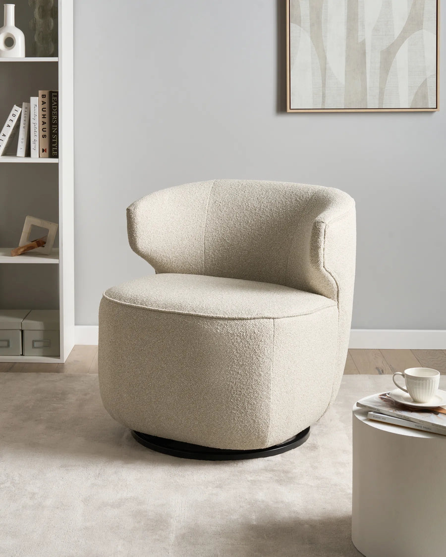 Beige armchair in a room with a bookshelf and coffee table.