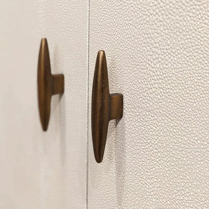 Close-up of two wooden cabinet knobs on a textured white surface