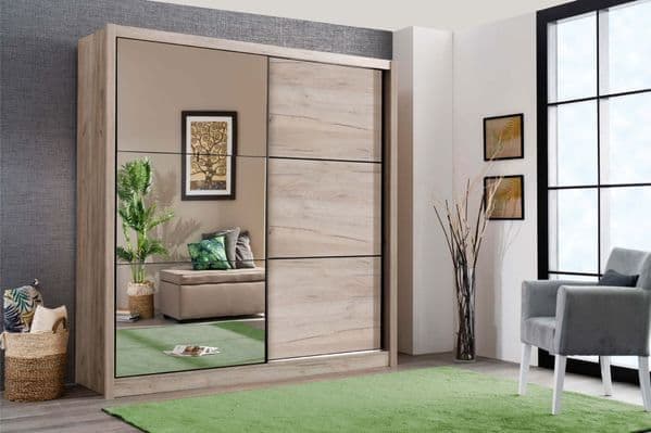 Wooden wardrobe with sliding doors in a room with a green rug and a chair.