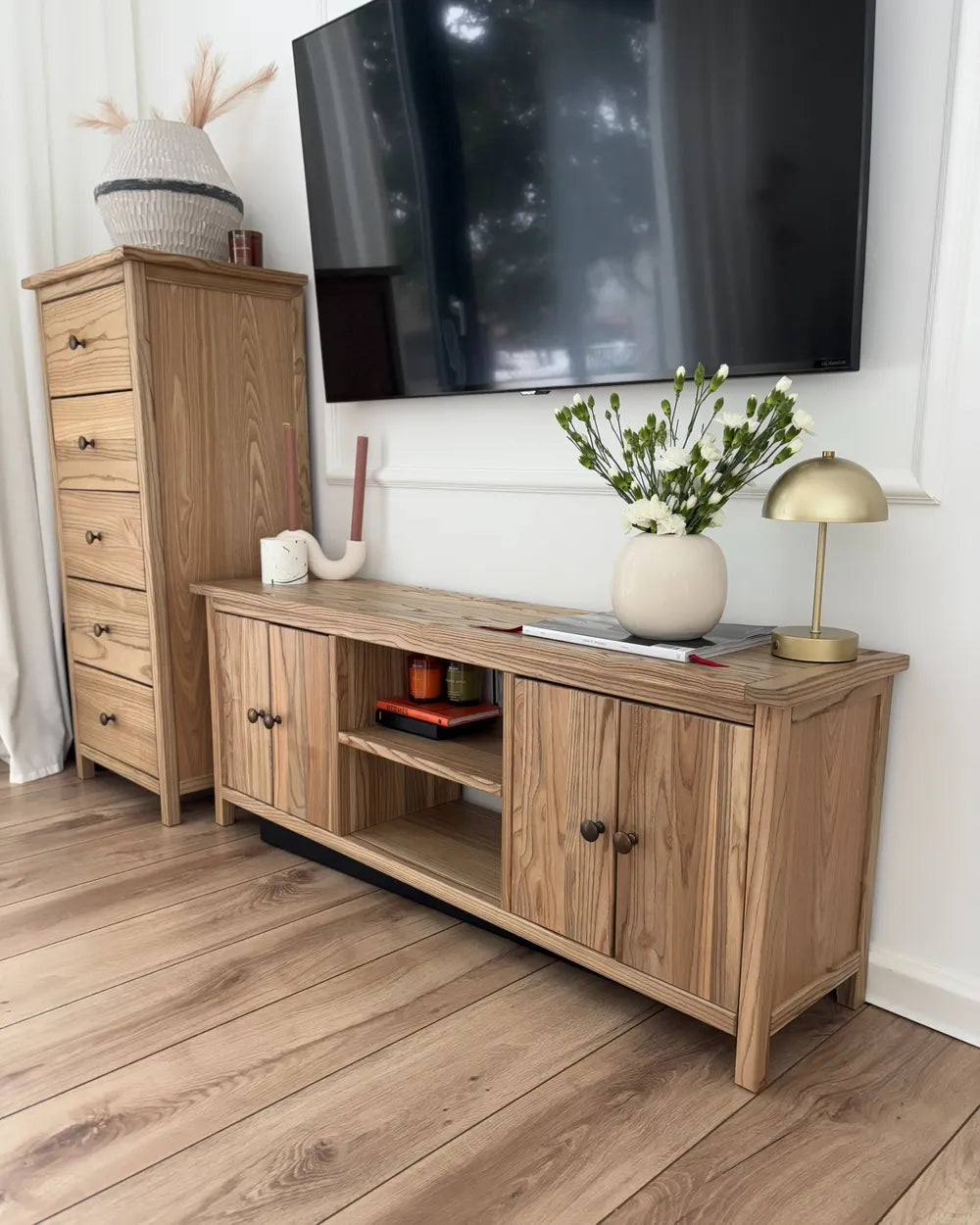 Wooden entertainment console with TV above, on a wooden floor.