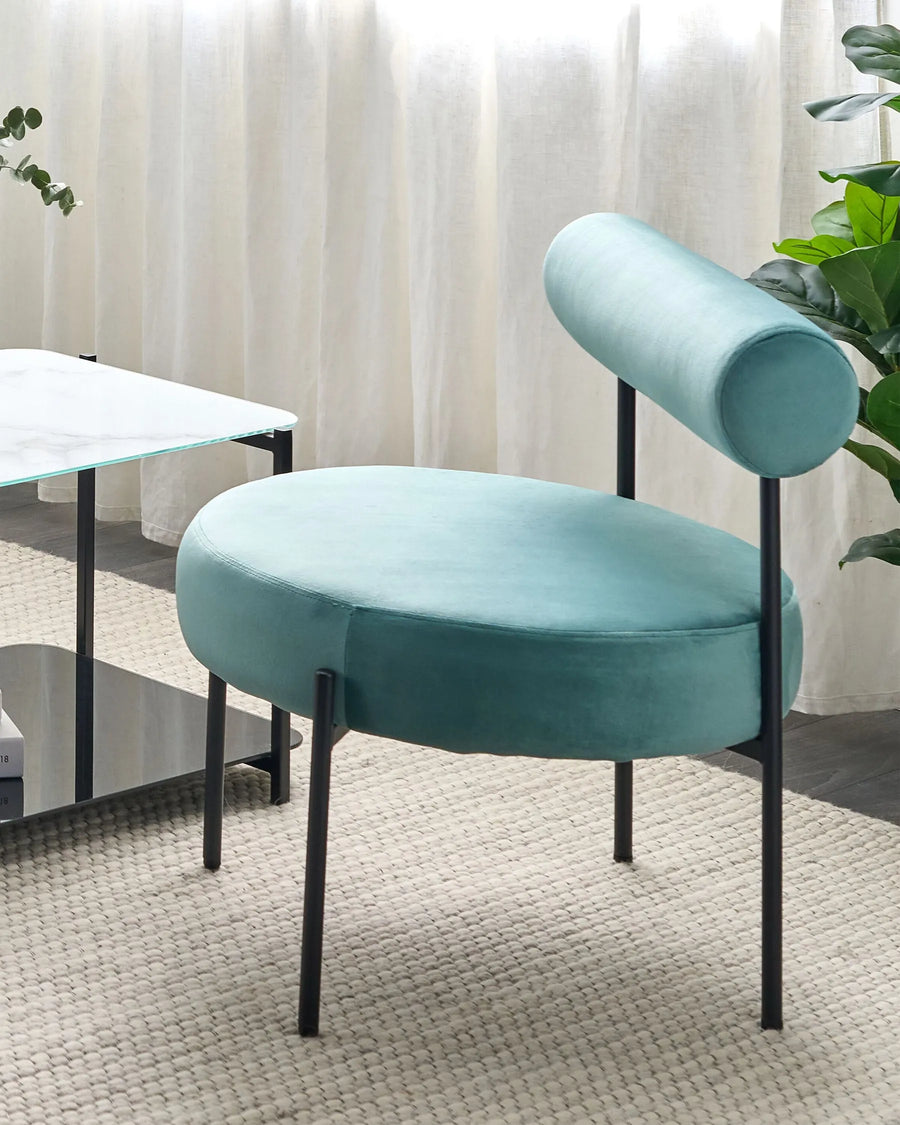Modern turquoise chair with black legs in a room setting