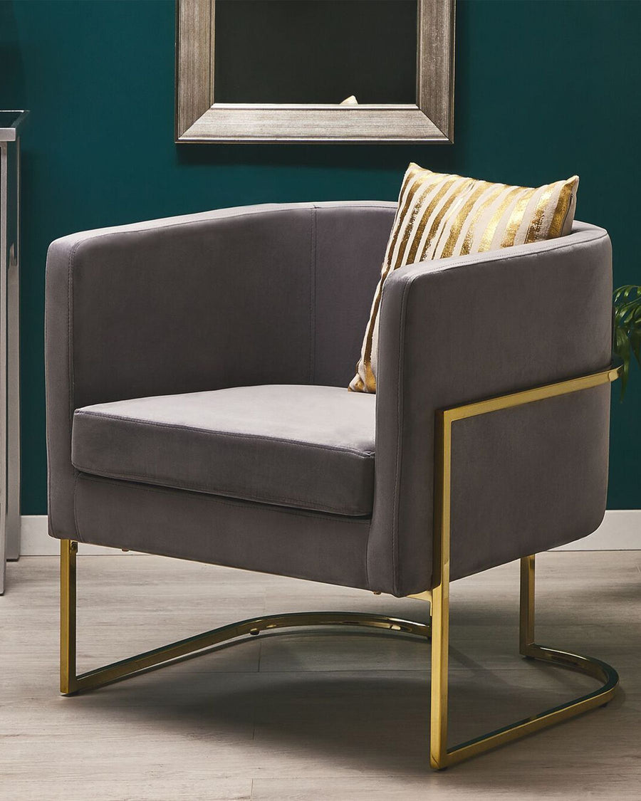 Gray armchair with gold legs and a striped pillow against a teal wall.