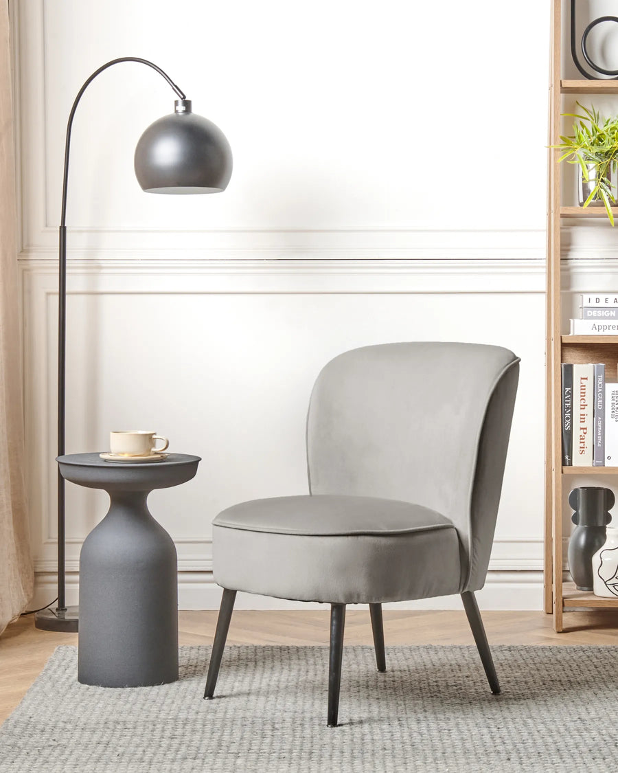 Gray chair in a modern living room with a side table and floor lamp.