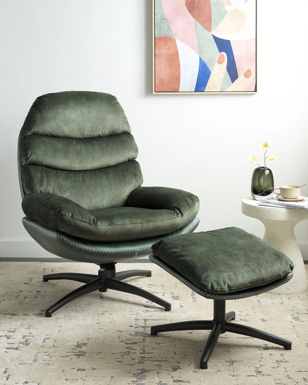 Green armchair with ottoman in a room with abstract art on the wall.