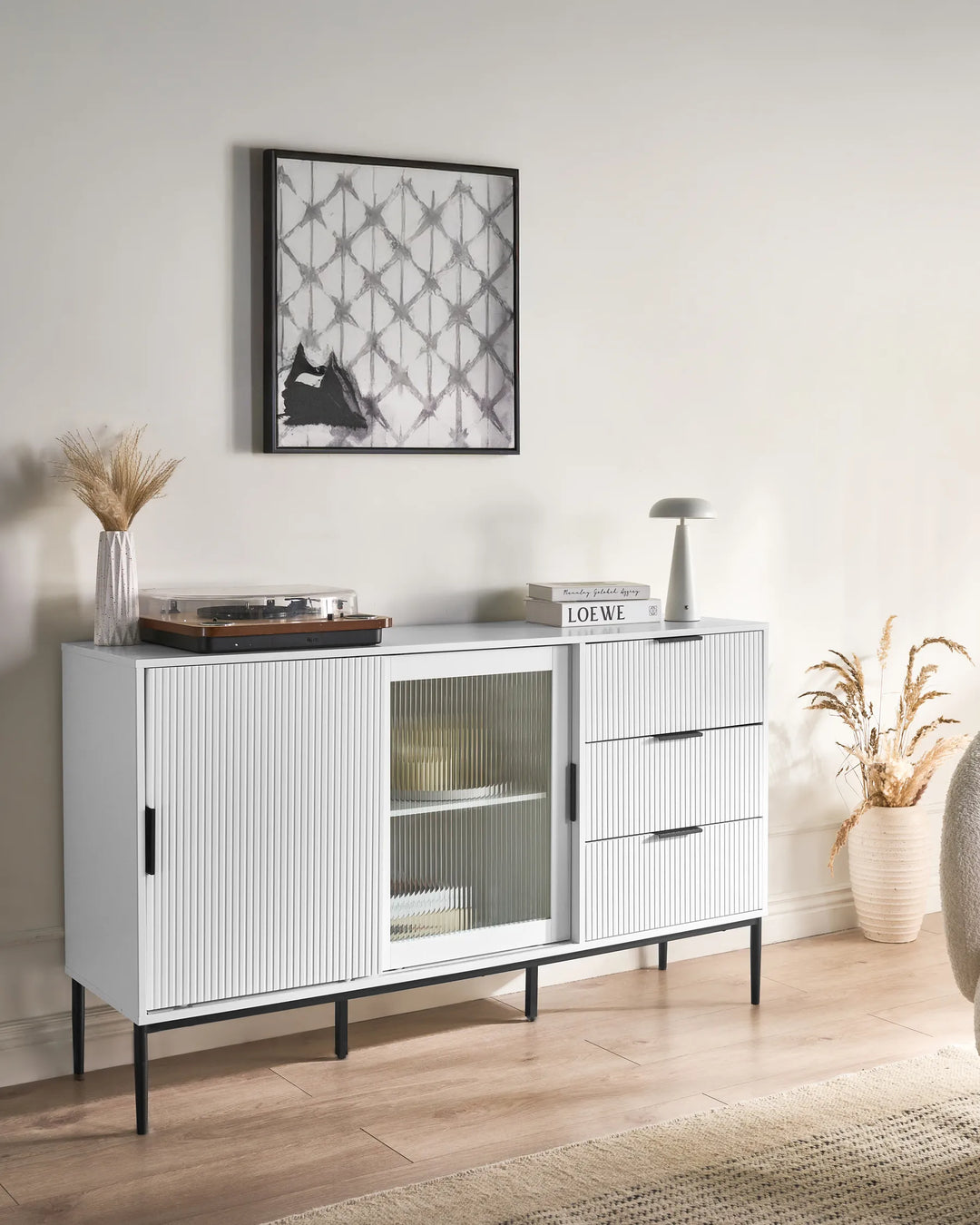 White sideboard with glass doors and drawers in a room with a framed picture on the wall.