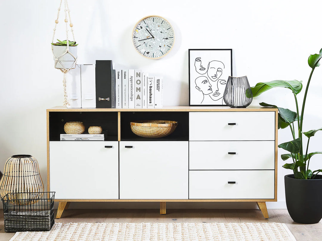 White sideboard with black accents in a room with decor elements like books, a clock, and plants.
