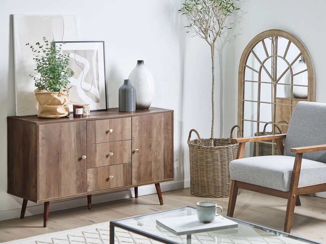 Wooden sideboard in a living room with a chair, coffee table, and decorative items.