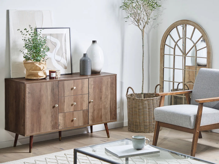 Wooden sideboard in a living room with a chair, coffee table, and decorative items.