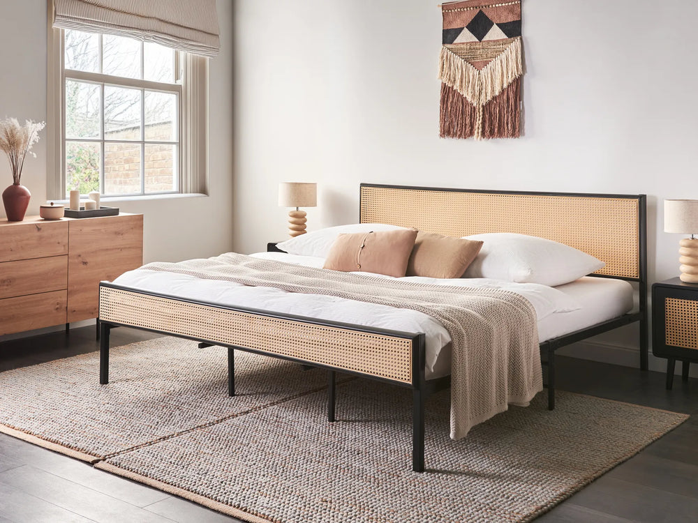 Bedroom with a bed featuring a wicker headboard and footboard, white bedding, and wooden furniture.