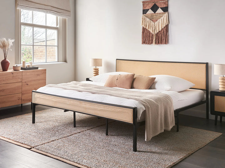 Bedroom with a bed featuring a wicker headboard and footboard, white bedding, and wooden furniture.