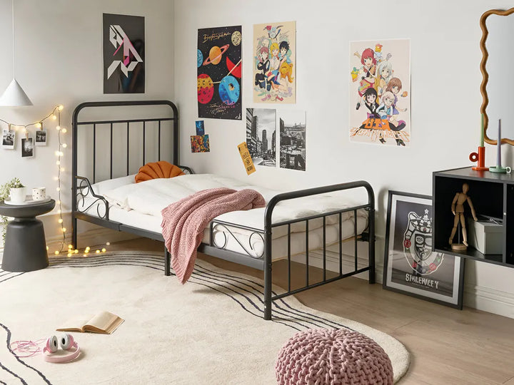 Bedroom with a black metal bed frame, white mattress, and colorful posters on the wall.