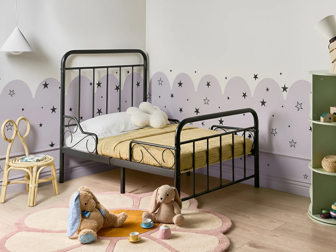 Children's bedroom with a black metal bed, teddy bears, and decorative elements.